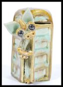 A Yare pottery dragon figurine depicting a dragon emerging from a phone box. Measures 11cm high.
