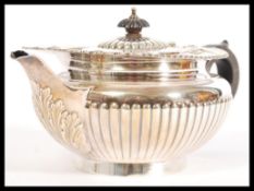 An early 20th century large hallmarked silver teapot having shaped black handle with reeded body and