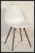A contemporary dining slide chair in the style of Eames DSW chair, having a white bucket seat raised