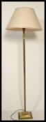 A brass Corinthian column standard lamp, with a cream lined fabric shade, on square base with paw