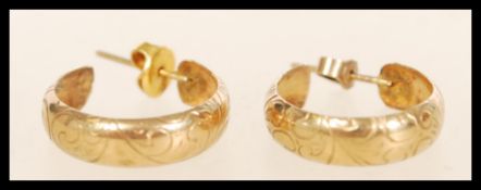 A pair of hallmarked 9ct gold earrings having scrollwork decoration. Complete with backs. Weighs 2.1