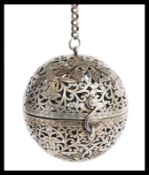 A Chinese / Tibetan silver white metal incense ball having scrolled decoration with birds of