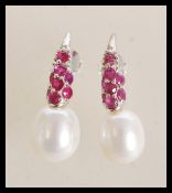 A pair of sterling silver freshwater pearl and ruby set drop earrings. Weighs 5.8 grams. 2.5cm long.