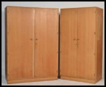 A mid century retro Meredew light oak pair of bedroom wardrobes. Each raised on plinth bases with