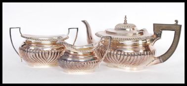 A silver plated tea service to include a tea pot with reeded decoration and ebonised wooden shaped