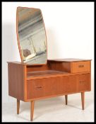 A 1970's retro Danish influence teak wood dressing table chests being raised on turned legs with two