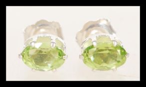 A pair of 925 silver earrings prong set with oval cut peridot stones.