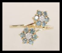 A hallmarked 10ct gold ring having a double flower head design set with white and green stones.