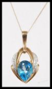 A hallmarked 9ct gold topaz and diamond pendant necklace, being set with a large pear mixed cut blue