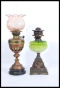 Two early 20th Century oil lamps to include a brass round base example with a pink glass shade to