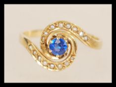 A stamped 18ct gold ring with a central prong set blue stone and seed pearl accent stones. Weight
