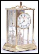 A 20th century brass anniversary clock with glass pane facia's enclosing an enamel faced dial by
