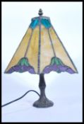 A vintage 20th century Tiffany style table lamp having a bronze effect Art Nouveau base with