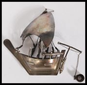 A silver / white metal model of a sailing box complete with sails moving bucket, rudder and ropes.