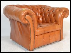 A vintage style sunburnt tan leather chesterfield armchair with a barrel rolled arms and backrest