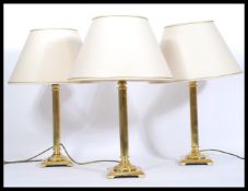 A set of three matching brass column table lamps, of Corinthian column form raised on a square
