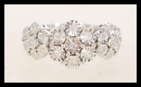 A hallmarked 9ct white gold triple cluster ring having three flowerheads of illusion set white