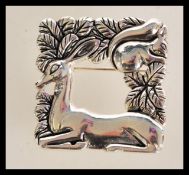 A sterling silver brooch in the manner of Georg Jensen. The open-squared brooch featuring a deer