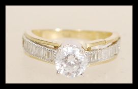 A hallmarked 9ct gold ring prong set with a brilliant cut white stone and square cut accent stones