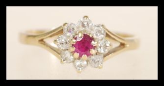 A hallmarked 9ct gold ruby and diamond ring set with a central ruby surrounded by a halo of diamonds