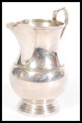 A 20th Century silver hallmarked creamer jug having a shaped handle and a stepped round base.