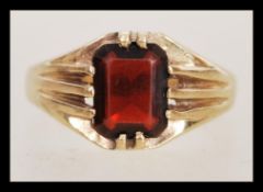 A hallmarked 9ct gold ring having a large faceted red stone with prong surrounds. Weighs 3.4 grams