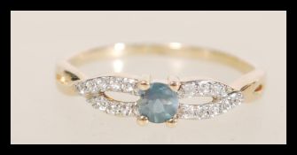 A hallmarked 10ct gold ring having a crossover design set with a central green stone and white