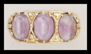 A hallmarked 9ct gold three stone ring having three inset faceted purple stones in scrolled heart