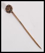 An early 20th century Edwardian 15ct gold stick pin having a flower head top with inset old cut