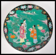 An early 20th Century Japanese Meiji period large porcelain charger having famille verte ground with