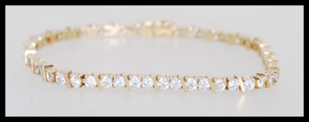A hallmarked 9ct gold tennis bracelet having a hidden clasp with fold over latch. Set with twin