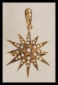A stamped 9ct gold pendant in the form of a star with seed pearl decoration with bale hoop atop.
