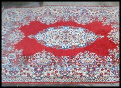 A Persian Islamic carpet rug on a red ground having one blue and cream floral medallion to the