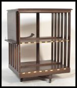 An Edwardian large mahogany revolving bookcase being raised on a four point swivel base with brown