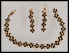 A demi-parure stamped 18ct gold bracelet and earrings set, having inset brilliant cut sapphires.