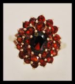 A hallmarked 9ct gold ring having a central faceted red stone with two halos of smaller faceted