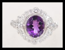 A sterling silver CZ and amethyst ring having a central faceted purple stone with a halo of white