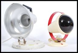 Two vintage retro 20th Century heat lamps raised on circular bases to include a Phillips with red
