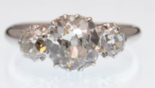 A three stone diamond ring. The ring set with a central old cut diamond of approx 1.63ct  flanked by