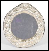 A sterling silver easel back photograph picture frame of circular form having rococo style relief