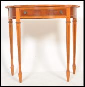 A 20th Century Regency style demi-lune side table having a bow front and single drawer with swing