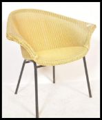 A vintage mid century Lloyd Loom batwing armchair being raised on angular supports and in the