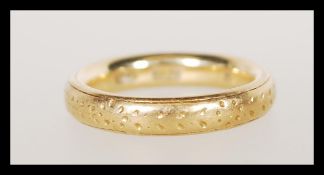A stamped 18ct gold band ring having floral engraving. Size I. Weight 5.6g.