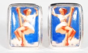 A pair of sterling silver cufflinks set with enamel pictorial panels depicting a pin up girl. Weighs