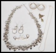 A collection of silver jewellery to include a  floral necklace, a pair of drop earrings set with