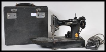 A vintage cased Singer feather weight electric sewing machine, model No 221 with various accessories