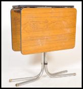 A retro tmid century teak formica and chrome drop leaf dining table being raised on tubular chrome