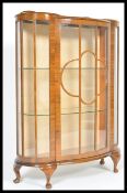 A 20th Century curved glass display cabinet raised on cabriole legs having bevelled glass sides. The