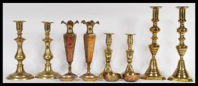 A collection of brass wears to include three pairs of candlesticks, a pair of brass vases with