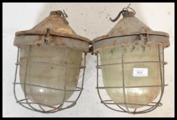 A pair of retro 20th Century industrial factory bulk cage lights, having a cast iron body, glass
